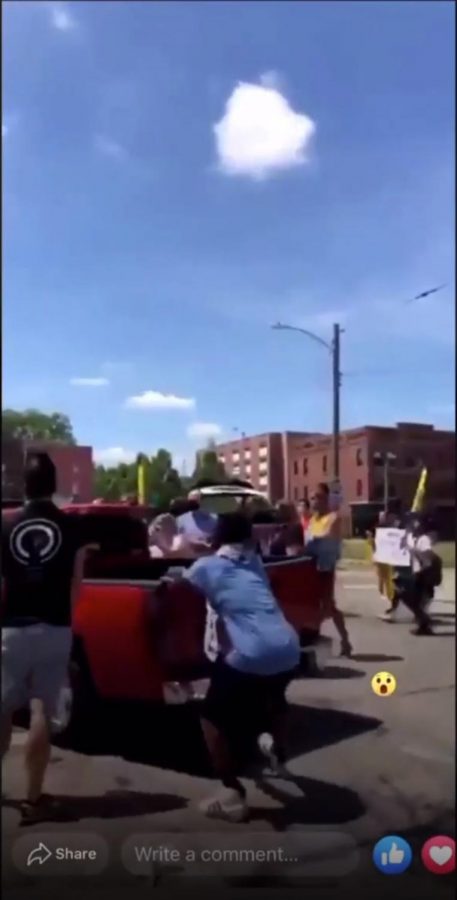A red pickup truck drives through a small protest outside of the Rogue Barber Shop on July 25. The Champaign County State’s Attorney will not be filing charges against the driver.