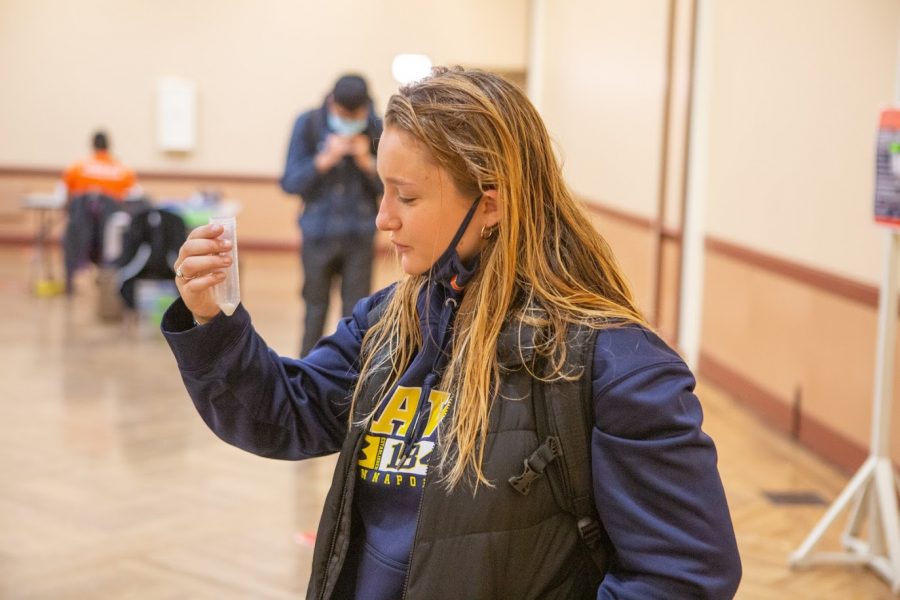Alexa English inspects her test tube to see how much saliva it contains while taking a COVID-19 test at the Illini Union on Sept. 30. Several testing sites will shift indoors beginning Monday.