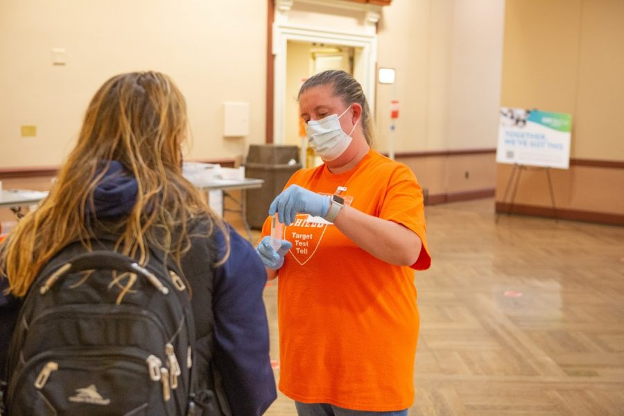 A University coronavirus testing worker hands student Alexa English her test tube in order to take a COVID-19 test at the Illini Union on Sept. 30.
