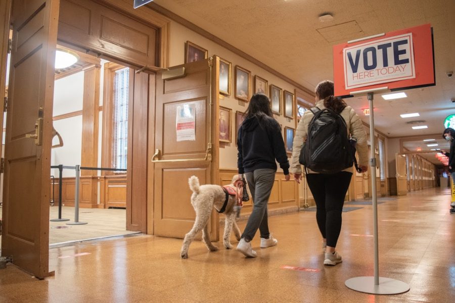 A pair of students walk past the entrance to a voting site located in Room 104 at the Illini Union on Oct. 23.
