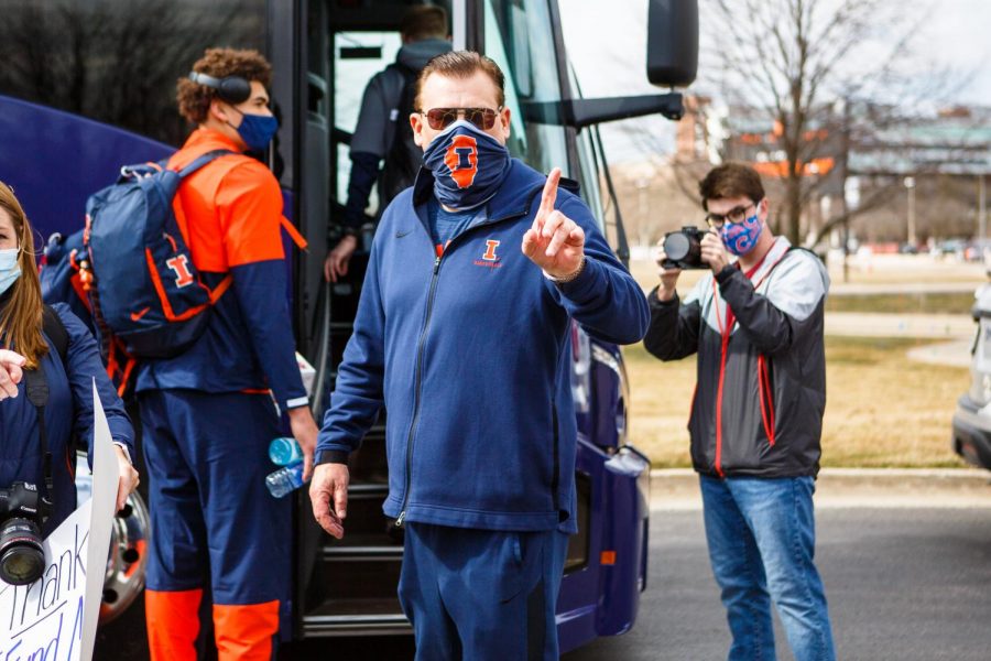 Brad Underwood holds up a number one before boarding a bus to Indianapolis prior to the Big Ten Tournament on Thursday. Underwood built up the Illinois basketball program through team-building and influential practice drills. 