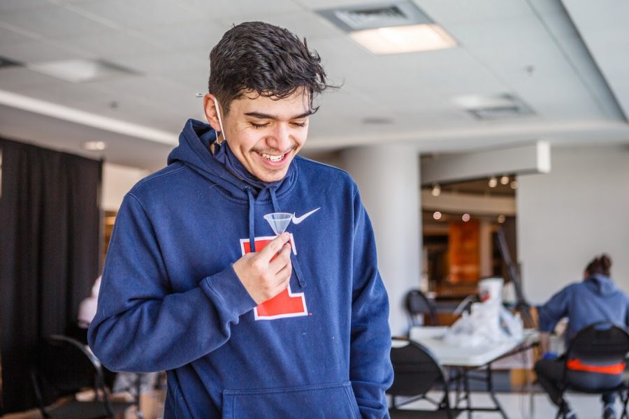 Jose Hernandez spits into his saliva sample tube in order to detect if he has COVID-19 on Feb. 1.  The University of Illinois has been working on upgrading the saliva test to include family members.