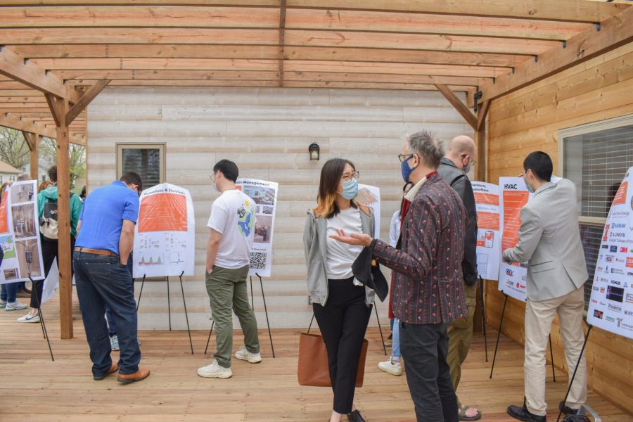 Students+of+the+Illinois+Solar+Decathlon+team+show+off+their+informational+posters+at+the+grand+opening+of+ADAPTHAUS+on+Saturday.+The+project+is+a+sustainable+solar-powered+home+that+lowers+carbon+emissions.