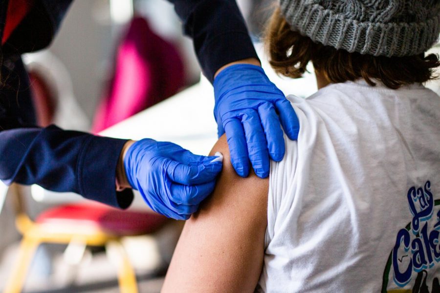 A Covid-19 vaccine worker puts a bandage on an individual who received the Moderna vaccination at the Church of the Living God on Feb. 20. A new study suggests that the spread of Covid-19 is linked to a possible rise/fall in mobility which is dependent on a series of variables. 
