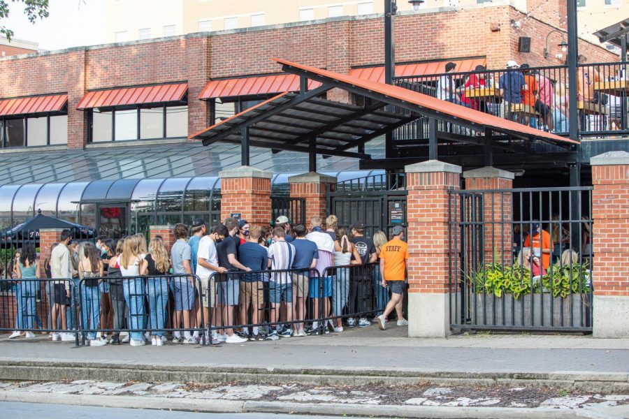 A group of students stand huddled in line outside of Joes Brewery on Sept. 17. Effective Friday, Champaigns bars and restaurants will be able to allow customers to stand and walk around.