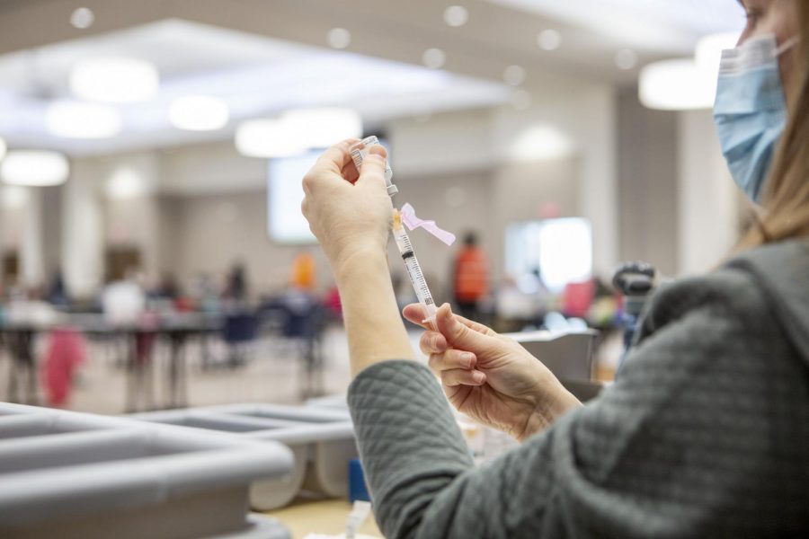 A woman fills up a syringe with a Moderna Vaccine at the I Hotel and Conference Center on Feb. 11. With a return to campus health officials expect a rise in cases and what that looks like for the University.