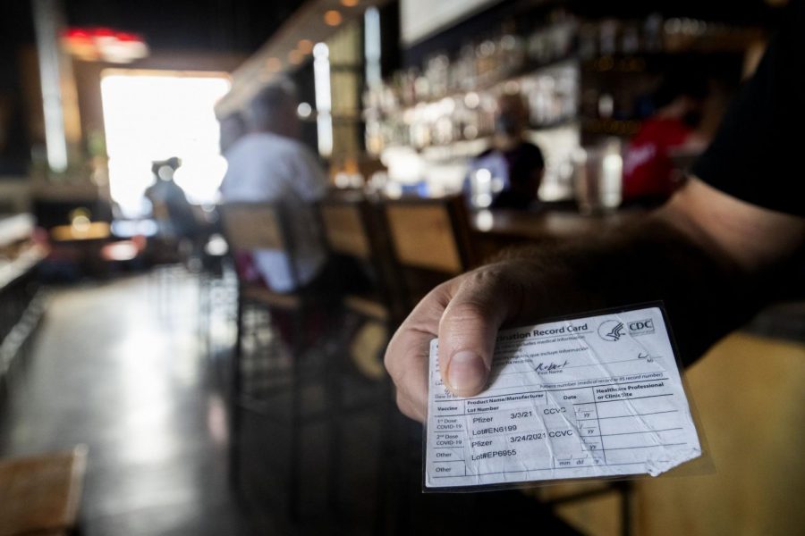 A person shows their vaccination card at a restaurant on Aug. 30. University students are concerned at the possibility that their peers have not gotten vaccinated and used fake vaccination cards to get away with it.