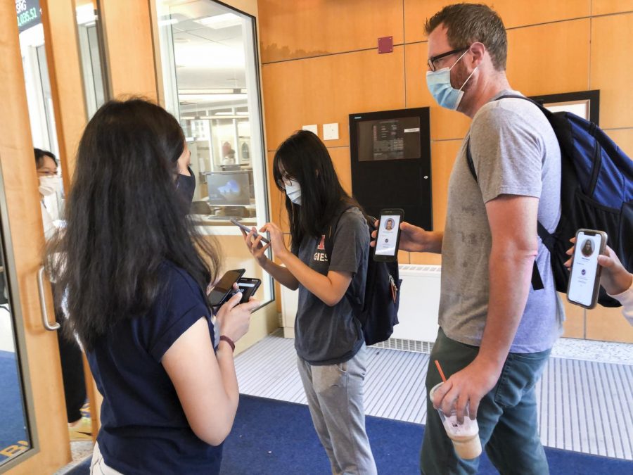 A University Wellness Associate checks two people into the Gies College of Business on Tuesday morning. The University has not hired enough Wellness Associates to be stationed at every building on campus, however, UI is still confident in their COVID-19 mitigation measures.