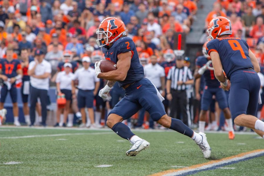 Running back Chase Brown sprints with the ball during the game against Wisconsin Oct. 9. Illinois football travels to Penn State this Saturday in hopes of a monumental victory. 