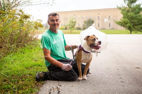 Champaign County Humane Society (CCHS) volunteer Joe Domain poses for a photo outside with Foster, an American Pit Bull terrier mix, after their morning walk Oct. 11. The CCHS is gradually restarting their volunteer program after the heat of the pandemic. 