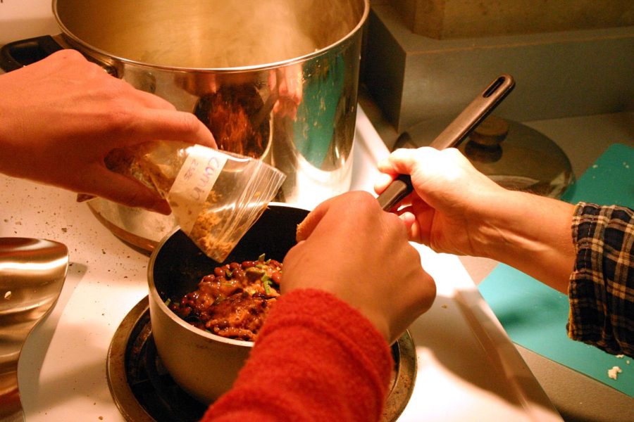 Two people hover over a pot making dinner on May 5, 2010. Columnist Chiara Awatramani believes it is better to save money by cooking at home then going out to eat.