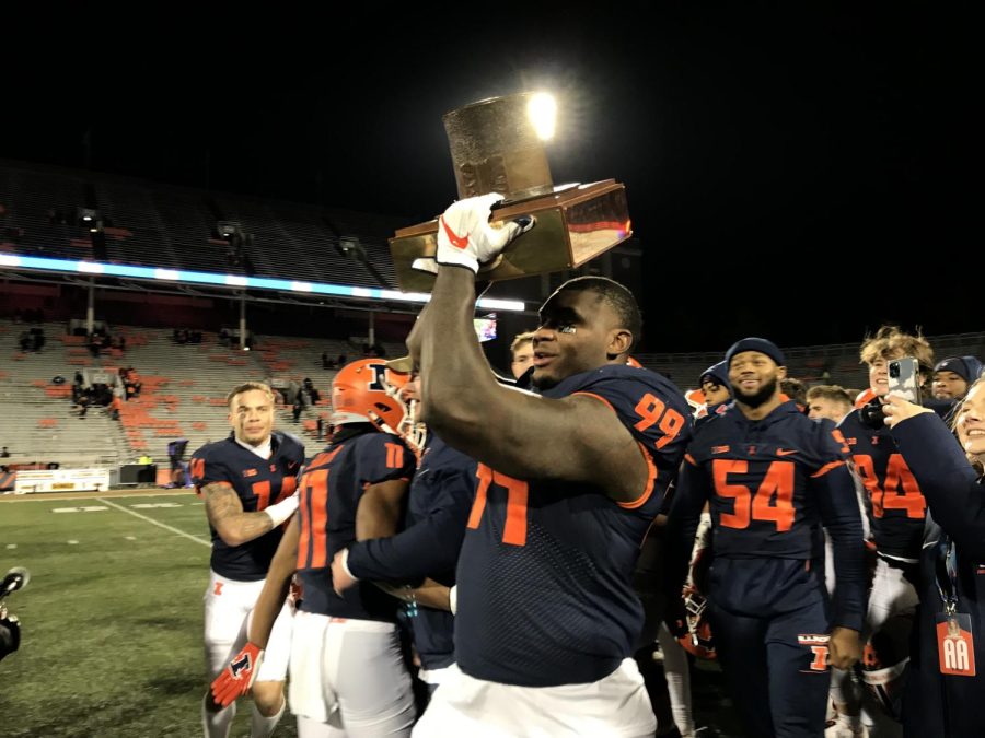 Owen Carney Jr. hoists the Land off Lincoln Trophy following Illinois 47-14 win over Northwestern at Memorial Stadium on Saturday evening.