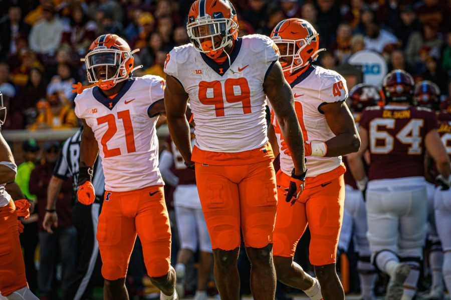 Owen Carney Jr. (99) celebrates with teammates Jartavius Martin (21) and Seth Coleman (49) during Illinois 14-6 win over No. 20 Minnesota in Minneapolis on Saturday. The defense dominated from start to finish, while Chase Brown and Brandon Peters played big roles on offense. 