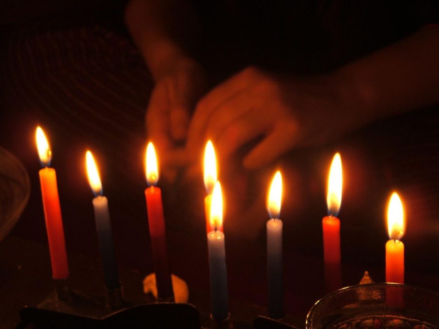 A person lights a candle on a menorah for Hanukkah at night. Students at the University have smaller celebrations for the Jewish holiday on campus because the eight-night event does not fall over winter break.