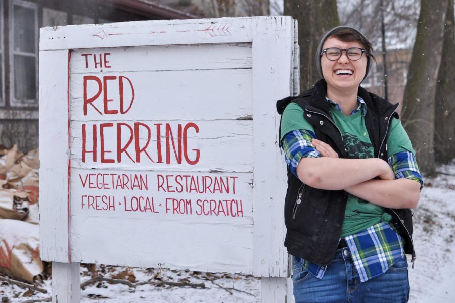 Red Herring owner, Lo Kolb, poses in front of the sign outside the restaurant. Kolb talks about their journey to owning the business and  future plans. 