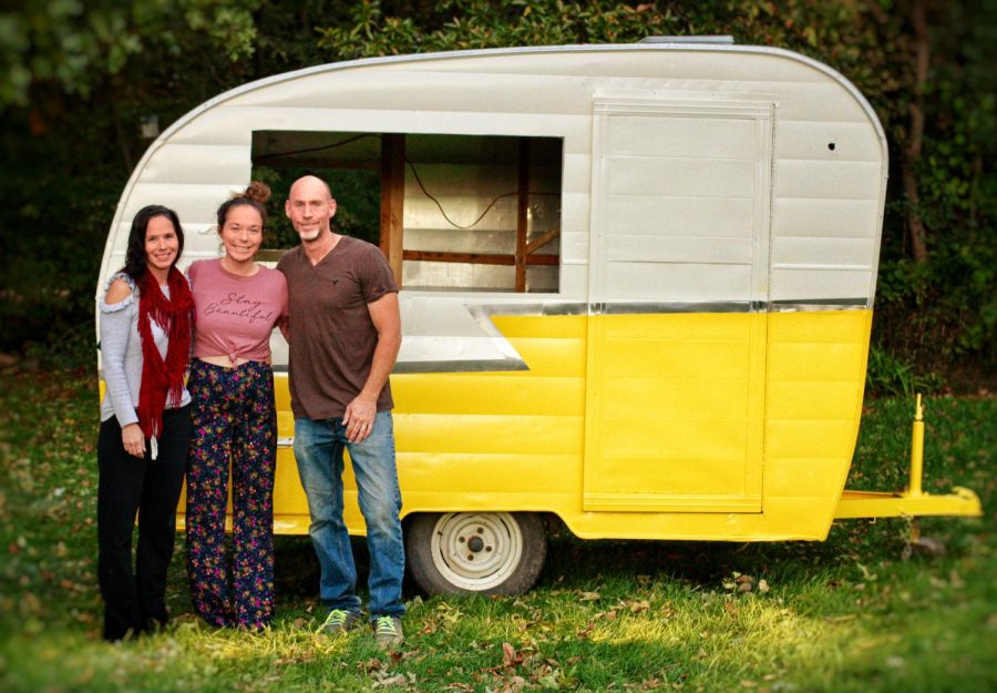 Just Bee Acai owner, Emma Curcuru, poses with her parents in front of the camper that would soon be their food truck. The business will be opening their store in the Illini Union on Friday. 