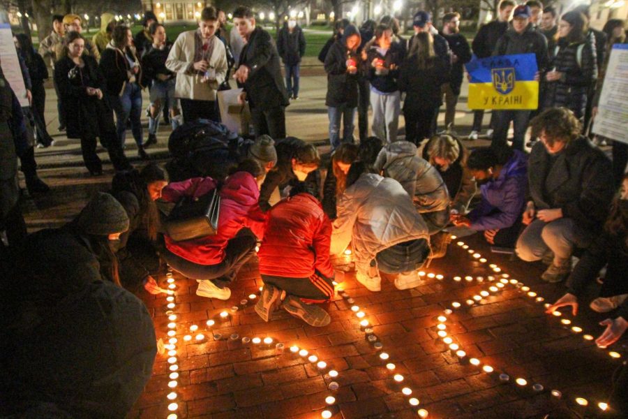 People gather around as others light up candles formed in the shape of the Ukrainian coat of arms on Thursday. The Ukrainian Student Association held the vigil to remember those who have passed due to the war in Ukraine.  