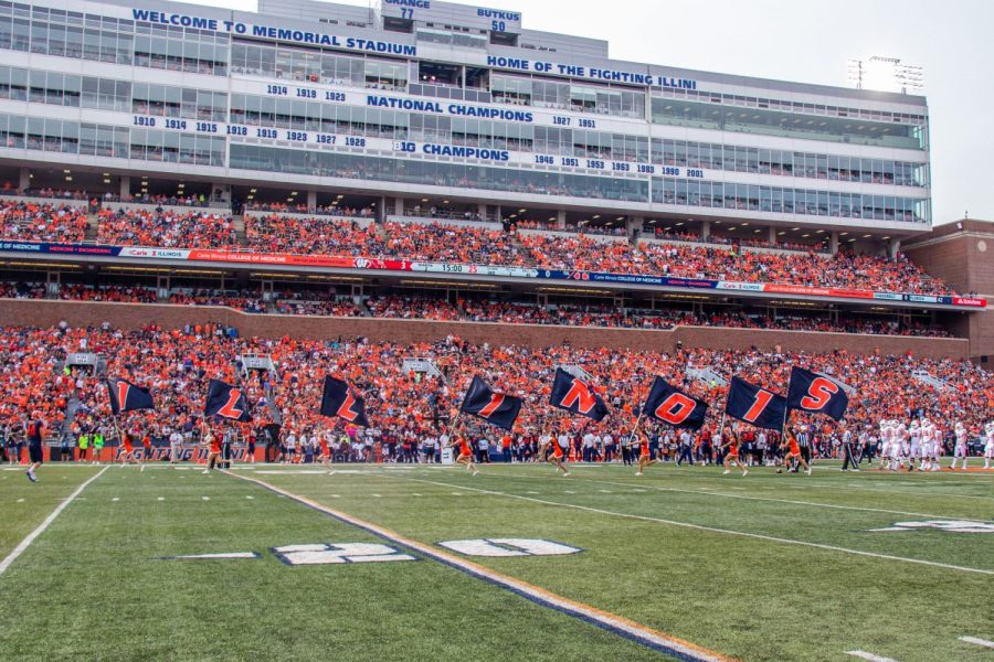 The+Illinois+Cheerleading+team+run+across+with+flags+spelling+out+Illinois+on+the+Memorial+Stadium+field+during+the+Homecoming+game+against+Wisconsin+on+Oct.+9.+The+the+University%E2%80%99s+Facilities+and+Services+has+started+the+process+in+replacing+the+turf+of+Memorial+Stadium+alongside+with+renovating+State+Farm+Center.+