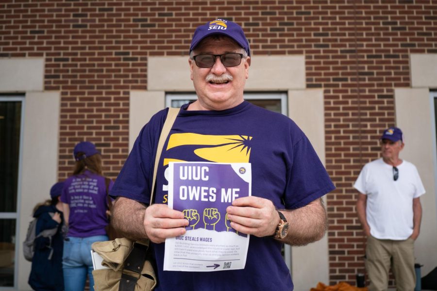 Scott Currid, member of the Service Employees International Union Local 73, holds a flyers during the SEIU protest in front of the Ikenberry Commons on April 29. 