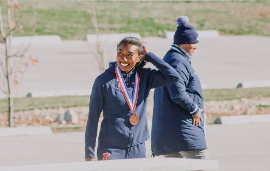 Distance runner OIivia Howell looks to her team with joy after receiving her first place medal during todays NCAA regional meet. Although Howell secured first place the rest of the team left more to be desired and missing the opportunity for the team to perform in nationals. 