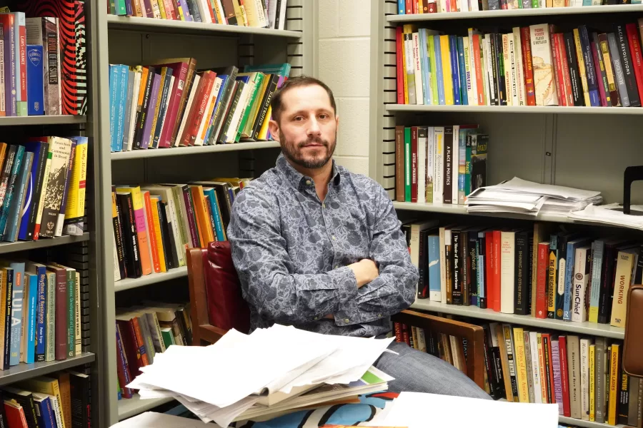 Marc Hertzman, associate professor in LAS, sits among a collection of books in his office in Gregory Hall. 