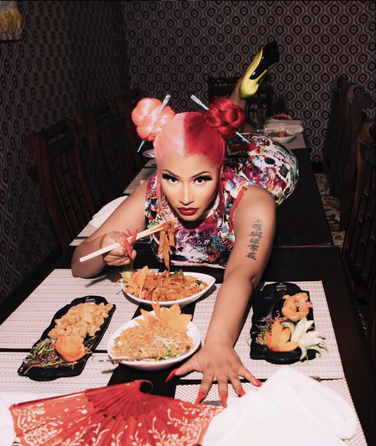 Rapper Nicki Minaj lies on top of a table eating Chinese food with a pair of chopsticks. Symbols of Asian culture are prevalent in the photo: her hairstyle has chopsticks stuck through double hair buns, there is a Chinese folding fan and she is showing her tattoo, which is in Chinese script. Columnist Vidhi Patel uses the example of Nicki Minaj to highlight how fame does not absolve people from accountability.