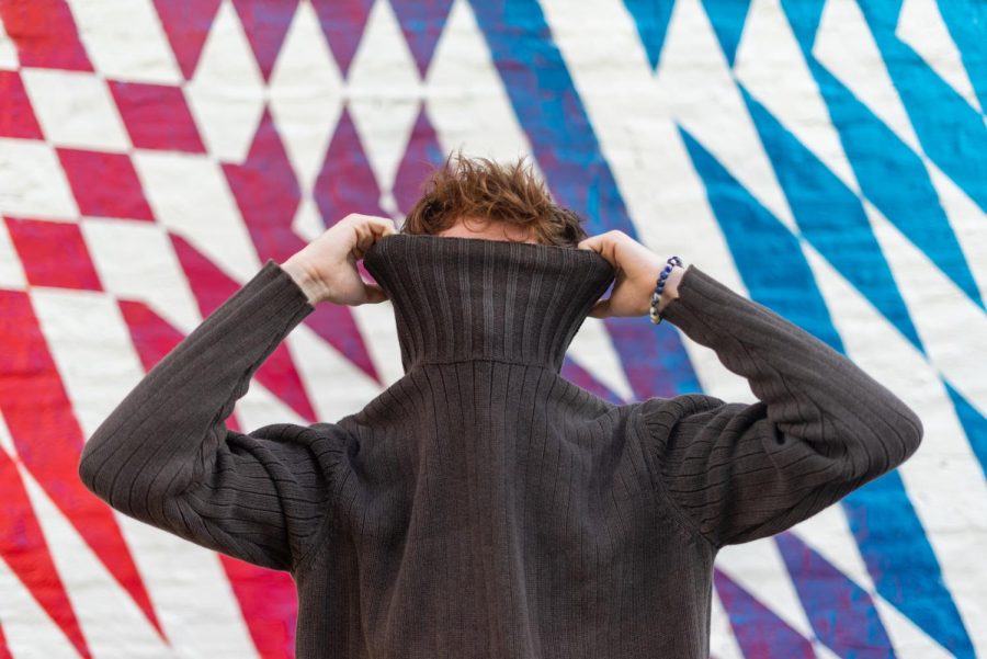 Charlie Anderson, freshman at Parkland College, pulls up a turtleneck in front of a mural off of South Fifth Street.
