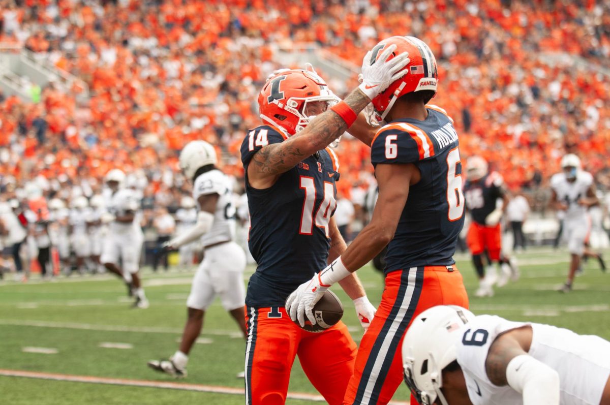Wide receiver Casey Washington and wide receiver Ashton Hollins celebrating by touching each others helmets. 
