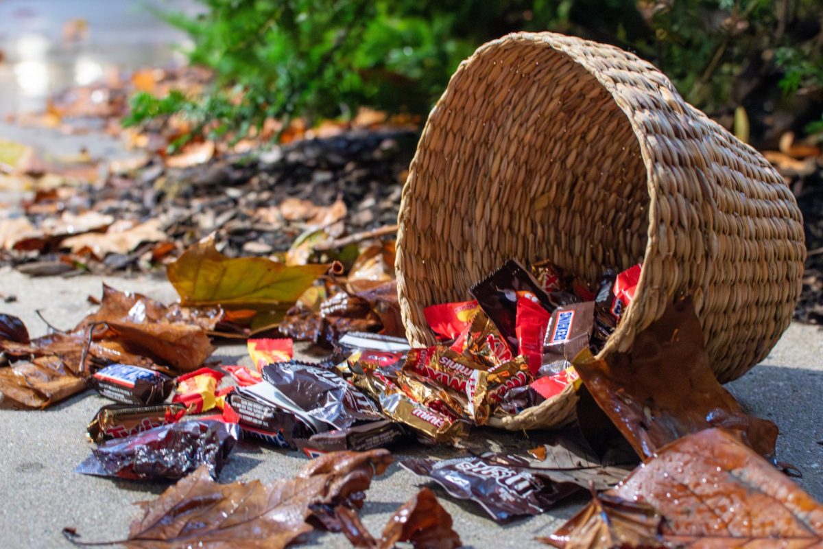 A basket full of popular Halloween candies spills onto the ground.