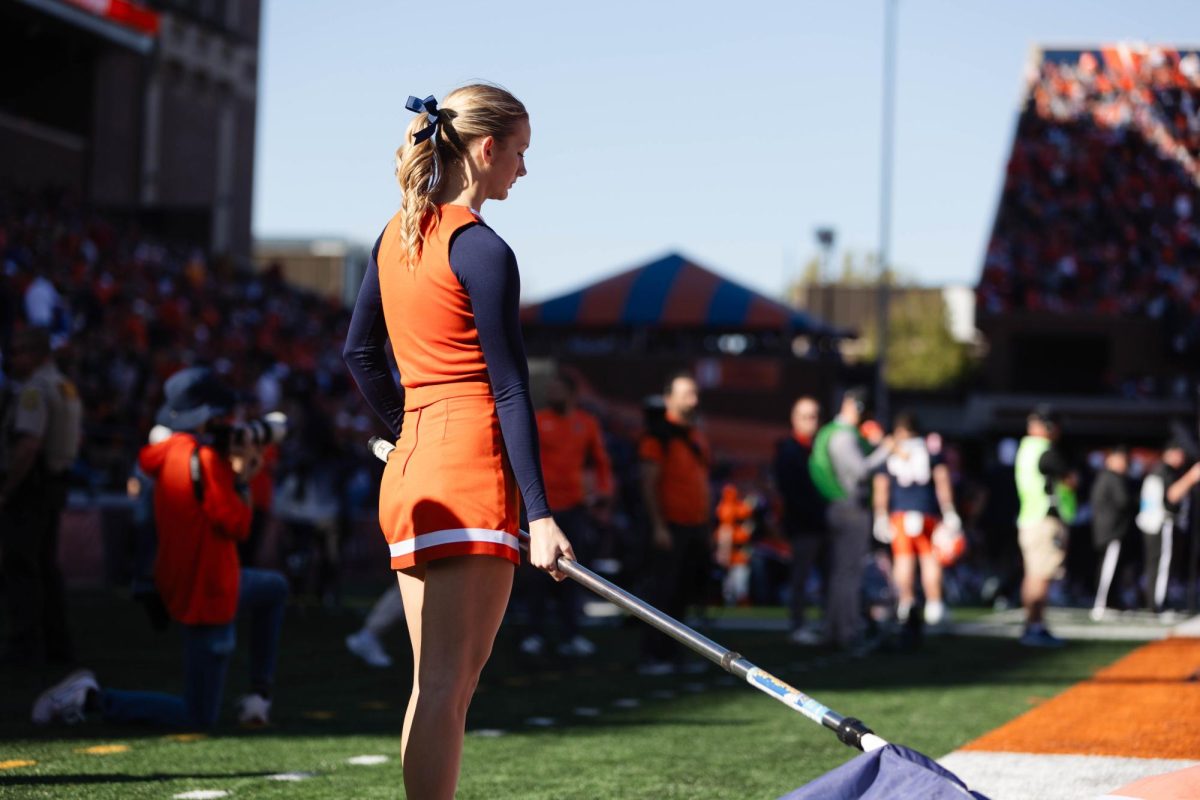 Cheerleading sophomore Paige Ingemunson rests with as flag in her hand as she prepares to get back on the field during a football game at Memorial Stadium on Oct. 21.