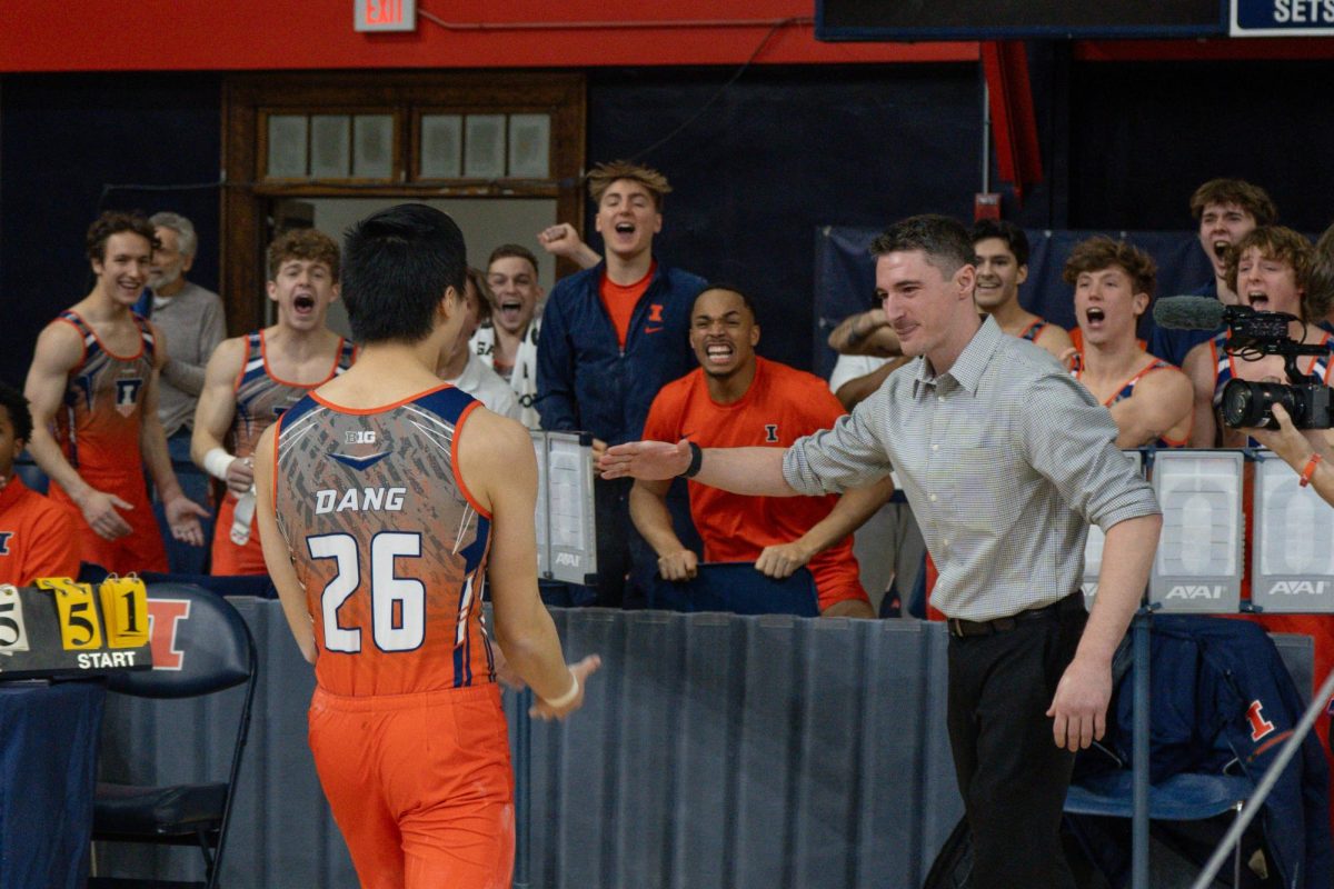 Freshman Brandon Dang rejoins an extatic team after completeing his pommel horse routine at the Illinois against Michigan in Huff Hall on Feb. 3. 
