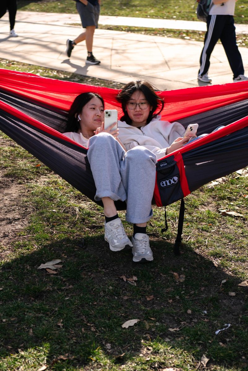 Janice Mei, sophomore in Engineering and LAS and Wendy Ruan, senior in Engineering relax on a hammock on the Main Quad as they browse on their phones on Monday afternoon.
