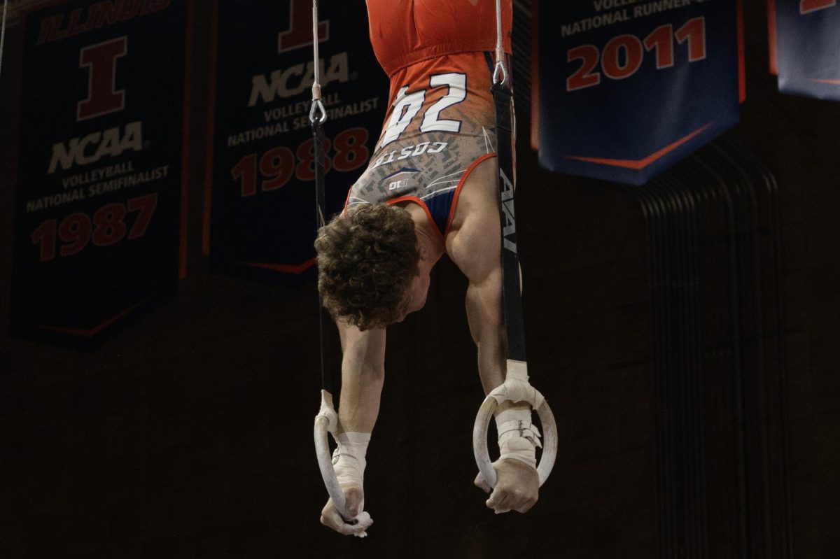 Sophomore Tate Costa balances a handstand on the rings during the meet against Michigan in Huff Hall on Feb. 11