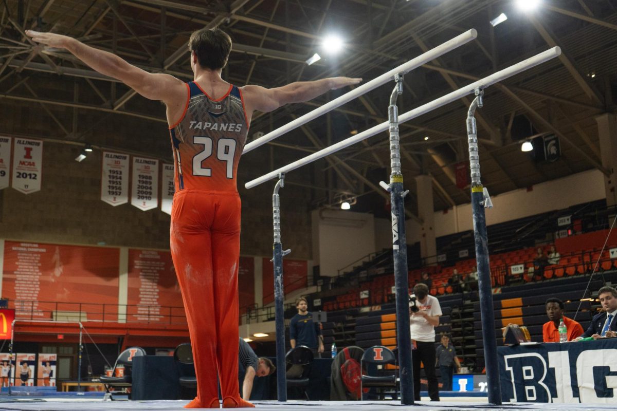 Freshman Alex Tapanes sticks the dismount of his parallel bars routine at the meet against Michigan at Huff Hall on Feb. 3. 