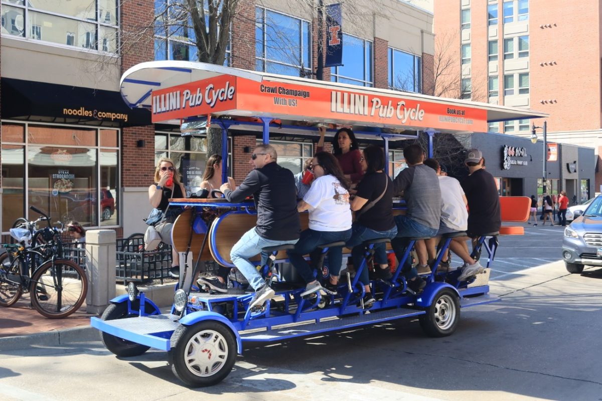 A group of moms and their children riding an Illini Pub Cycle on Green Street, Saturday, April 13.