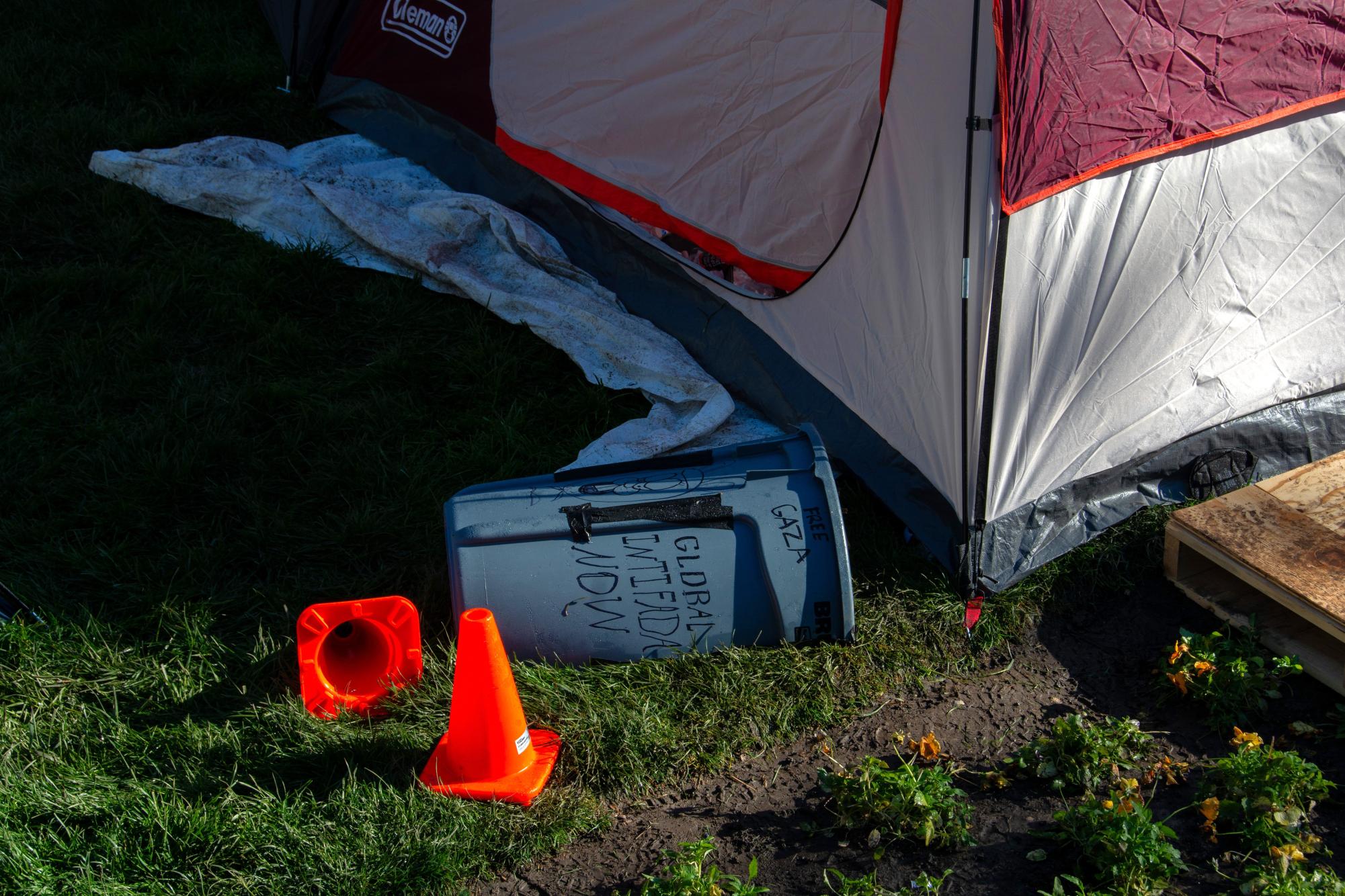 A makeshift shield lays next to cones and a tent on Tuesday morning at the Main Quad as the Palestine encampment continues to carry through the week.