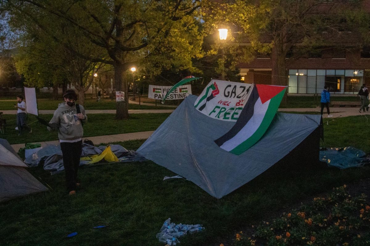 Protester walks through the tents assembled in front of Foellinger Auditorium Monday night.
