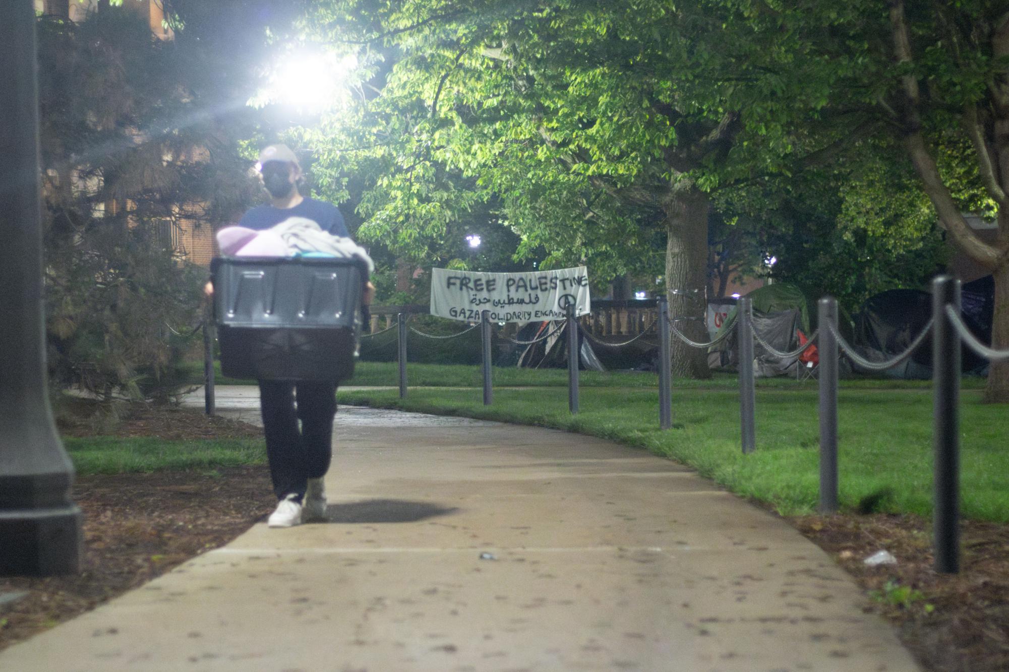 Protester relocates a bin from the encampment to nearby restaurant The Red Herring on Friday.