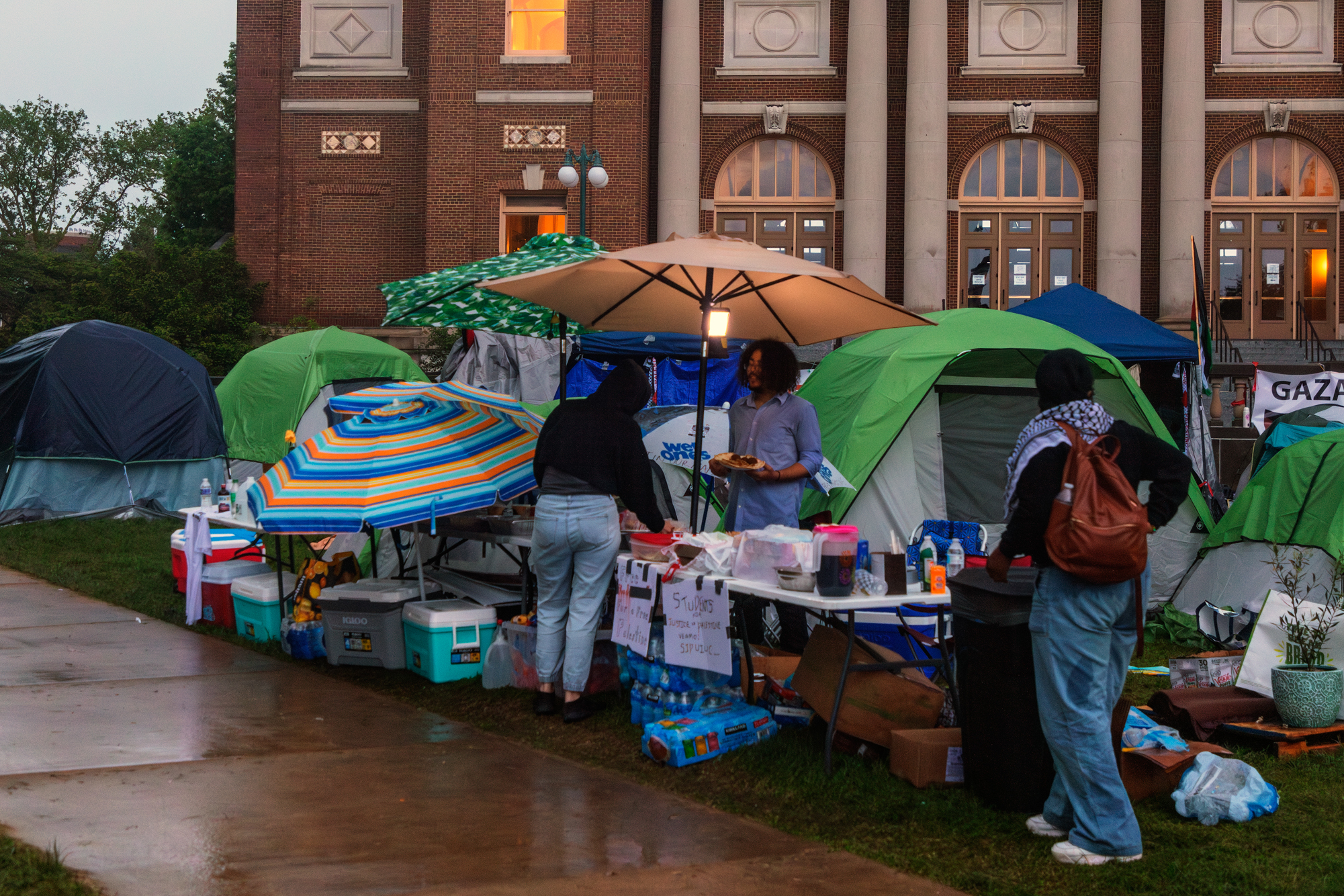 Protesters hand out food in front of Foellinger Auditorium during the rain fall on Saturday.