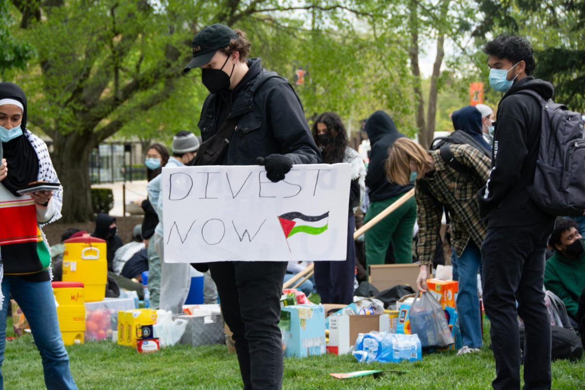 A+pro-Palestine+protestor+holding+up+a+sign+that+reads+%E2%80%9Cdivest+now%E2%80%9D+at+the+SJP+encampment+near+Alma+Mater+on+April+26.+The+University+invested+more+than+%2427+million+in+companies+linked+to+the+war+in+Israel+and+Gaza+in+2023.