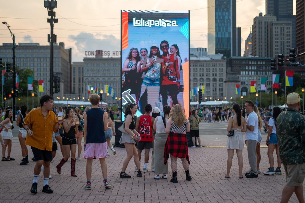 Festival attendees take a photo on a large, centrally located screen at Lollapalooza on Aug. 4.




