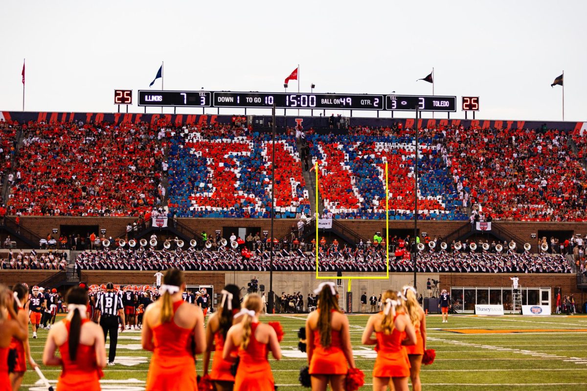 As the second quarter of a football game against Toledo on Sept. 2 comes close to its start, the Illini student section hold up signs collectivle forming "INI." 