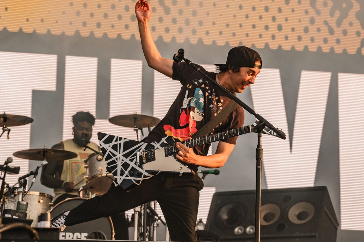 Vic Fuentes skips forward with guitar in hand.