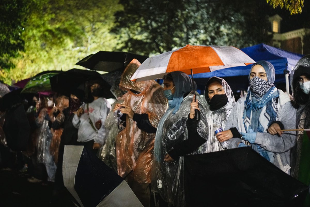 Protestors link together in the rain during a protest at Alma Matter on Aug. 26. The protest was in support of Palestine and called out for the University to divest.