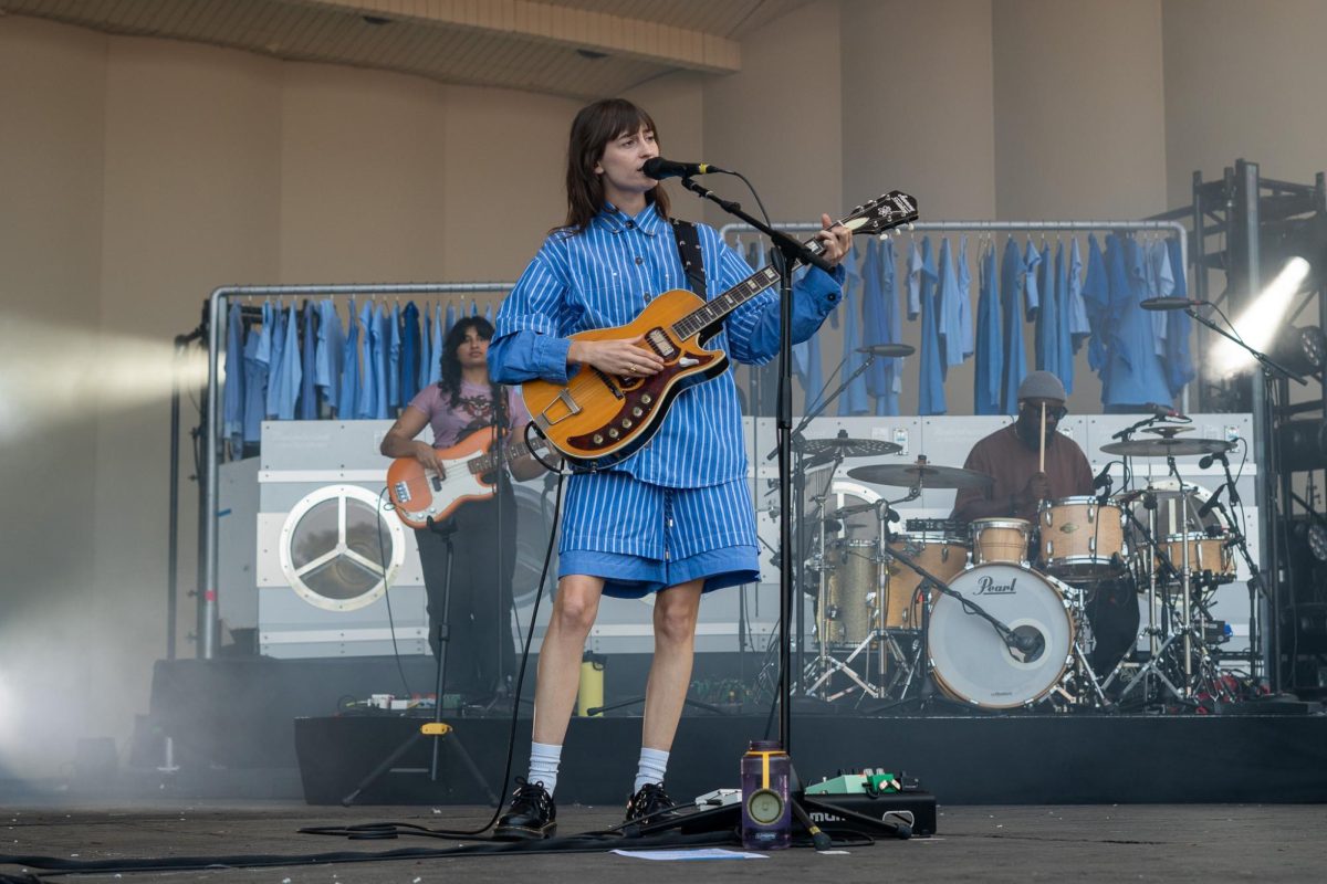 Faye Webster performs at Tito's stage on Aug. 2 featuring a background set of multiple glowing laundry machines and dozens of hanging blue shirts.