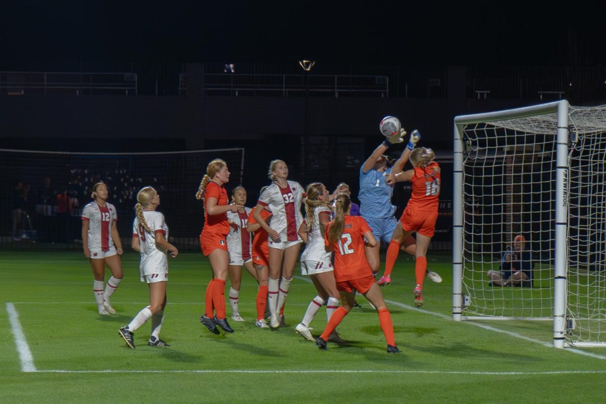 Both teams scramble as the Illini shot on goal nearly goes in. Wisconsin junior goalie Drew Stover blocks the shot as Illinois junior Sarah Foley attempts to header the ball in.