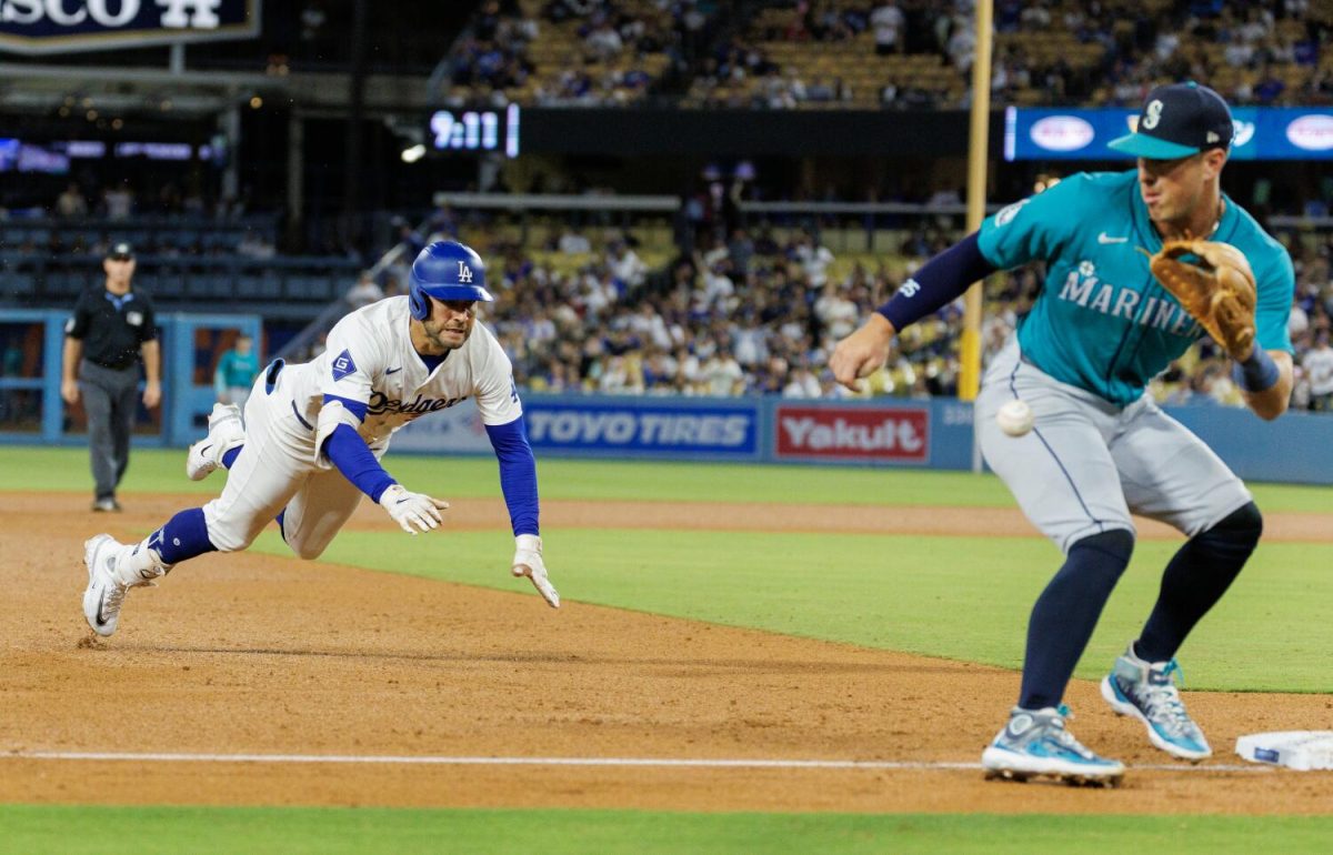 Los Angeles Dodgers outfielder Kevin Kiermaier (93) dives safely into third base as Seattle Mariners after hitting a triple as Seattle mariners third base Josh Rojas (4) receives the ball inside the baseline in the sixth inning at Dodgers Stadium on Aug. 21, 2024 in Los Angeles, California. 