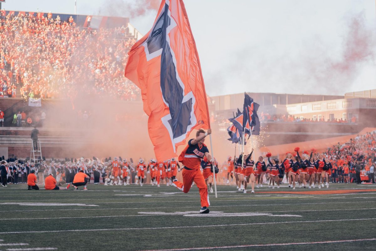 An Illinois cheerleader runs onto the field with a Block I flag before Illinois’ upset win over Kansas.