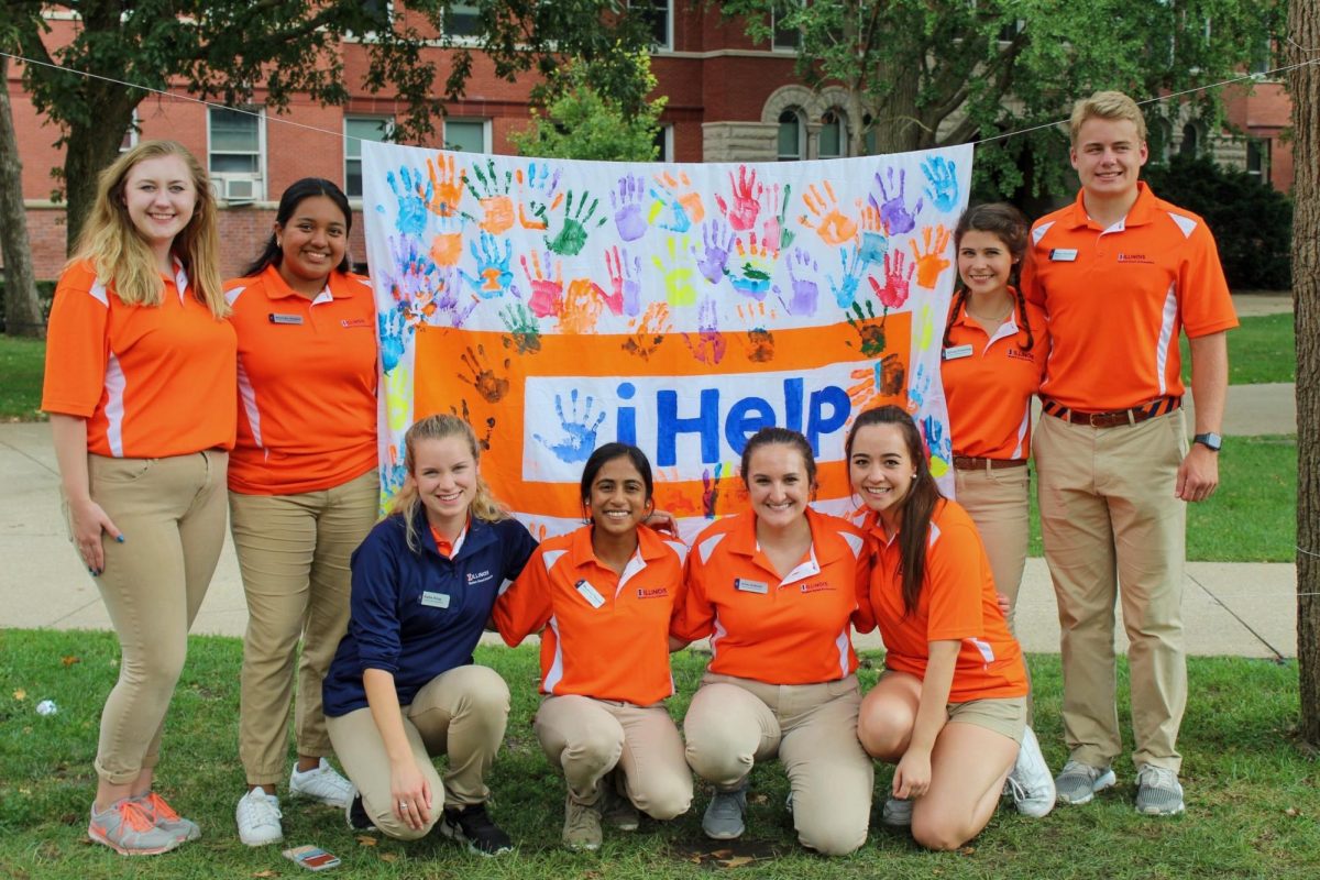 Illinois Student Alumni Ambasadors stand holding an iHelp flag from 2023's iHelp day of service.