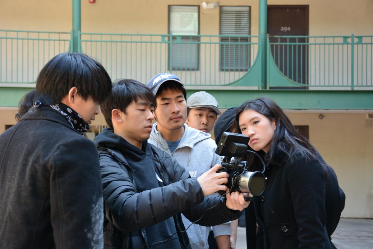 The cast of “Wind Walker” gathers around Director Daniel Zhang on set while shooting.